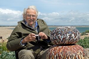 John Hitchens photographed with his work with a beach background