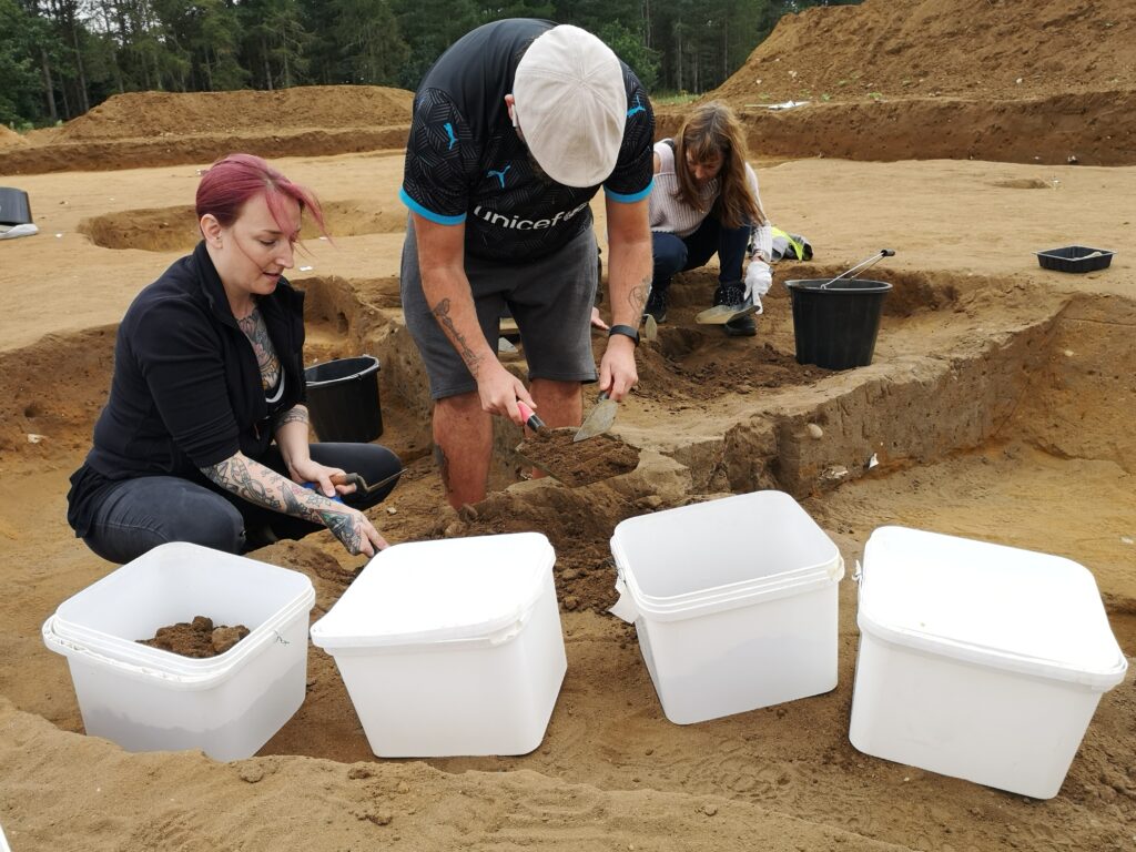 Image of volunteers putting soil samples into white tubs as part of the Rendlesham excavations